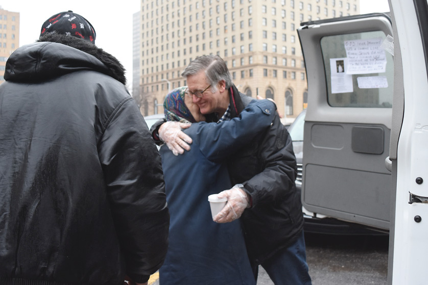 Bill Hill receives a hug from a woman as he hands out coffee with the St. Aloysius street ministry team in downtown Detroit on March 10. Hill is a member of the Ignatian Volunteers at Manresa, which offers retirees a chance to give their time in service to local nonprofits. Dan Meloy | The Michigan Catholic