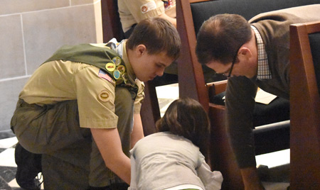 Proving a scout's work is never finished, a young man bends to pick up a stack of pamphlets during the annual recognition Mass for scouts March 6 at the Cathedral of the Most Blessed Sacrament. Dan Meloy | The Michigan Catholic