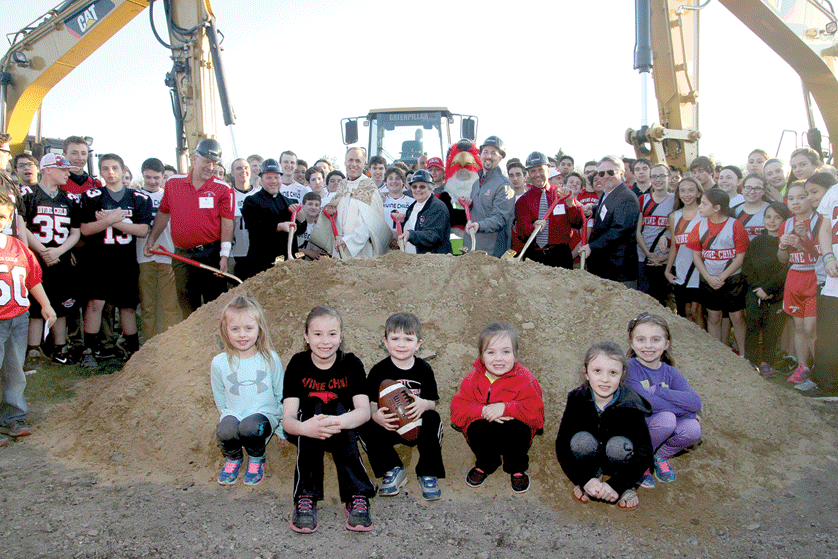 Students, staff, and faculty pose after the ceremonial "first dig" on a new $3 million athletic facility at Dearborn Divine Child High School on April 15. John Vena | Special to The Michigan Catholic 