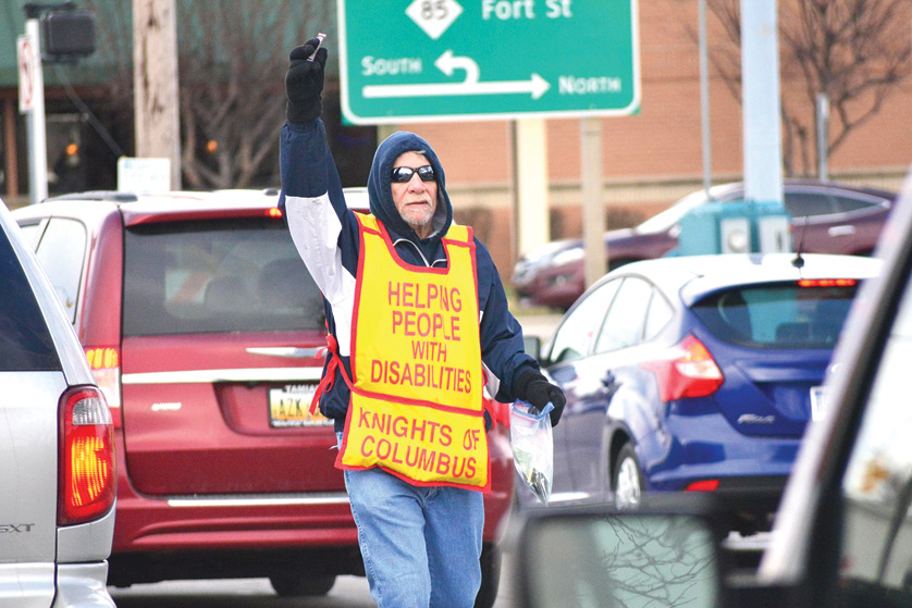 Gary Sorice, a member of Knights of Columbus Council 1802 in Wyandotte, offers Tootsie Rolls to drivers at the corner of Eureka and Fort streets March 19. The semiannual drive, held the weekend of Palm Sunday and Columbus Day, benefits a multitude of charities that help the mentally and physically disabled. (Mike Stechschulte | The Michigan Catholic)