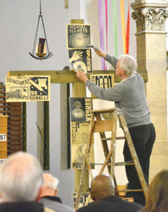 A man nails “exploitation” to the cross before Good Friday services at Our Lady of the Rosary Parish in Detroit. (Mike Stechschulte | The Michigan Catholic)