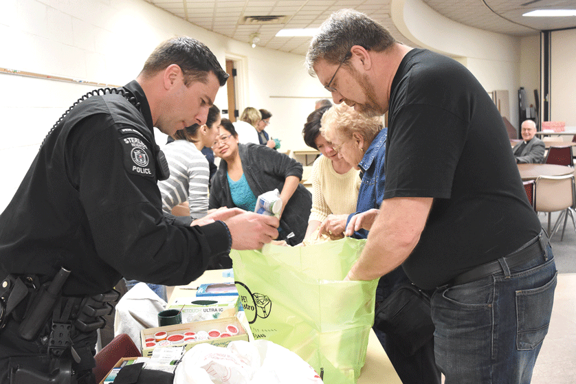 Sterling Heights Police Officer Remie Verougstraete and Mark Kilgore, program coordinator of Greater Macomb Project Vox, sort through prescription drugs turned in April 30 during a National Drug Take Back Day event at St. Michael Parish in Sterling Heights. Dan Meloy|The Michigan Catholic