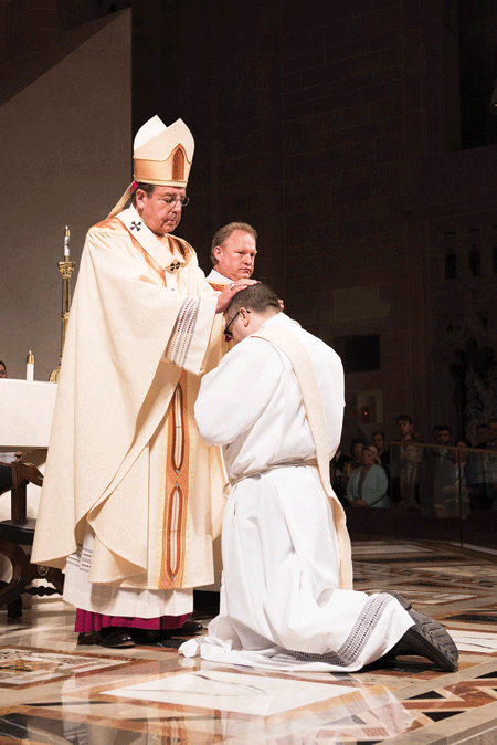 Archbishop Allen H. Vigneron lays his hands on Fr. Timothy Wezner to ordain him to the sacred priesthood May 14.