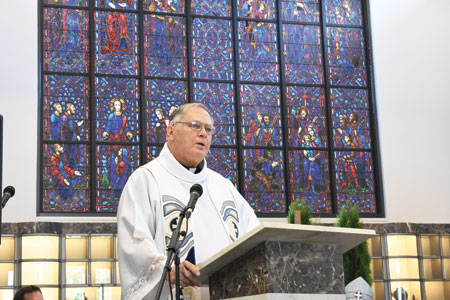 Fr. Tim Babcock, liaison for the Archdiocese of Detroit's Catholic Funeral and Cemetery Services, speaks during the June 18 dedication of the St. John Paul II Mausoleum at Our Lady of Hope Cemetery in Brownstown Township. Behind him is a stained glass window transported to the new mausoleum from the now-closed Our Lady of Lourdes Church in River Rouge. Photos by Dan Meloy  | The Michigan Catholic