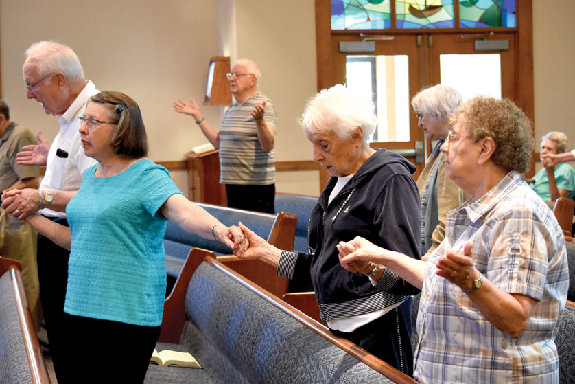 Residents hold hands during the Our Father at a Communion service inside the chapel at Henry Ford Village in Dearborn.