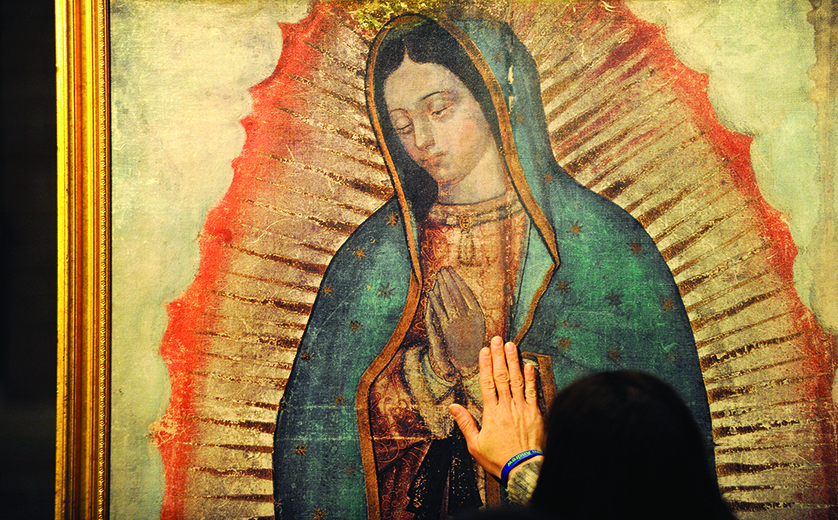 A woman lays her hand on a traveling missionary image of Our Lady of Guadalupe during a visit by the replica to St. Louis Church in Pittsford, N.Y., Oct. 28. The digital image is a reproduction of the image left on the tilma of St. Juan Diego in present-day Mexico City in 1531. (CNS photo/Mike Crupi, Catholic Courier) (Oct. 31, 2012)