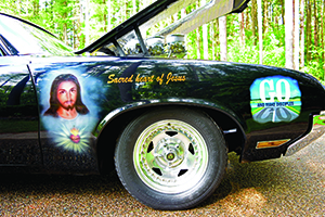 The Sacred Heart of Jesus and the words “GO, and make disciples” are painted on the right front fender of the Hatmakers’ hot rod.