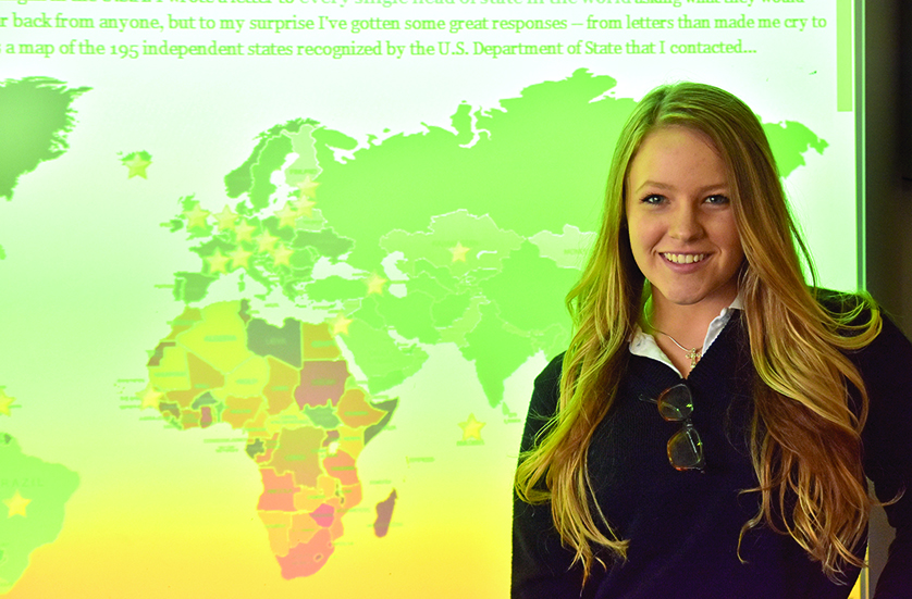 Hunter Maclean, who graduated from Marian High School in May, stands next a world map depicting the countries that have responded to her project, during which she wrote every head of state in the world asking for advice for America’s teenagers.