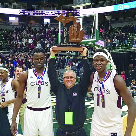 Fr. Karl Kiser, SJ, outgoing president of University of Detroit Jesuit High School, hoists the state championship trophy on the court after his Cubs won the Class A basketball title in March.