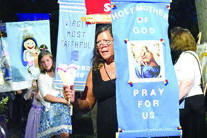 A woman carries a banner in a Marian procession after Mass to mark the Feast of the Assumption at Assumption Grotto Parish in Detroit. For more photos, visit gallery.themichigancatholic.com.