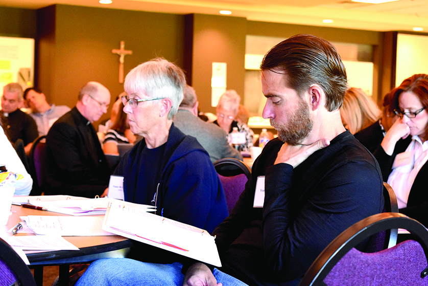 A synod member looks over the materials presented Sept. 24 during a gathering of synod members in the archdiocese’s Northeast Region at St. Isidore Parish in Macomb. The regional gathering, which will be followed by three others in the archdiocese’s Northwest, South and Central regions, was the first opportunity for synod members to gather together to pray, listen and ask questions about the specific themes and topics to be discussed at the synod itself in November.