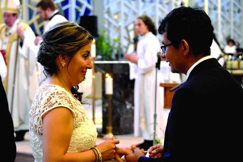 A couple smiles at each other as Archbishop Allen H. Vigneron leads the blessing and exchange of rings during a joint wedding Mass on Aug. 27 involving 17 couples at St. Damien of Molokai Parish in Pontiac. The joint wedding was the result of the parish’s push to encourage cohabiting and civilly married Catholics to tie the knot before God and His Church.