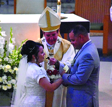 Archbishop Vigneron lends his microphone during a couple’s exchange of vows Aug. 27 at St. Damien of Molokai Parish.