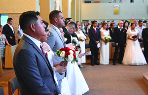 Couples stand in a semi-circle around the altar at St. Michael Church of St. Damien of Molokai Parish on Aug. 27 during a joint wedding Mass.