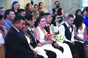 A woman smiles as she takes in the special day Aug. 27 during a wedding Mass for 17 couples at St. Damien of Molokai Parish in Pontiac.