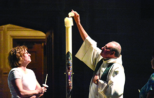 Fr. Duane Novelly lights a candle during a prayer service at the cathedral during “Summer Nights,” which brought together music ministers from across the archdiocese.