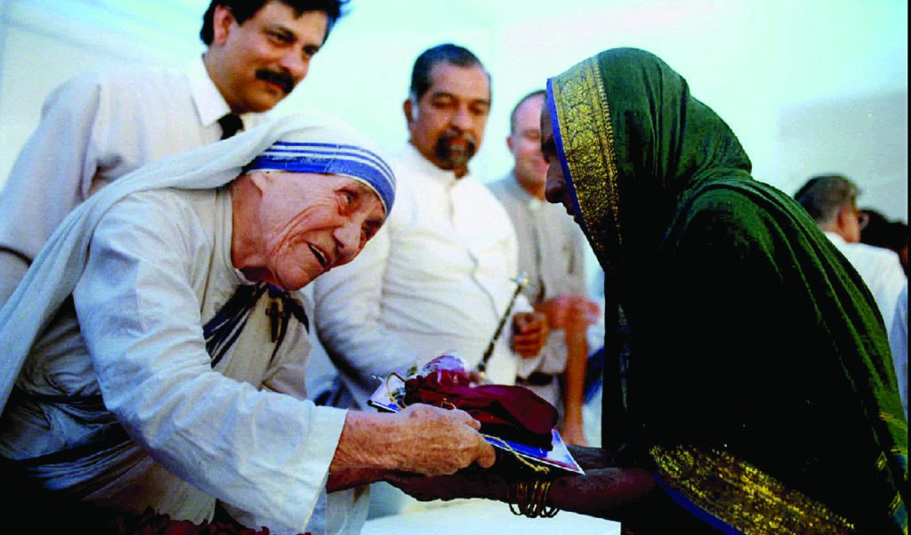 Blessed Teresa of Kolkata, India, presents documents for a new house to a villager in 1994 in Mumbai, formerly Bombay. Mother Teresa will be canonized by Pope Francis Sept. 4 at the Vatican. (CNS photo/Luciano Mellace, Reuters) REUTERS/Savita Kirloskar/File Photo