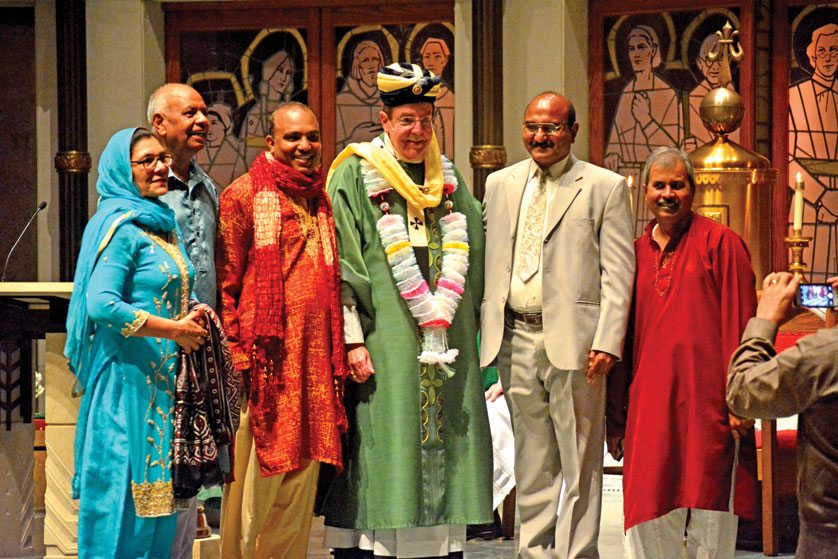 Archbishop Allen H. Vigneron poses for pictures with members of the Pakistani community at St. Jude Parish in Detroit, who presented him with a traditional garland and turban during the parish’s 75th anniversary Oct. 29. (Mike Stechschulte | The Michigan Catholic)
