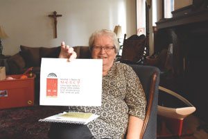 Sr. Mary Ellen Howard, RSM, former executive director of the St. Frances Cabrini Clinic in Detroit, holds a sign highlighting the Jubilee Year of Mercy.  The sign reads, "Become a door of mercy through which those who enter may experience the love of God." (Dan Meloy | The Michigan Catholic)