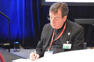 Archbishop Allen H. Vigneron takes notes as he listens to synod members’ insights during the parishes portion of Saturday’s synod session. (Dan Meloy | The Michigan Catholic)